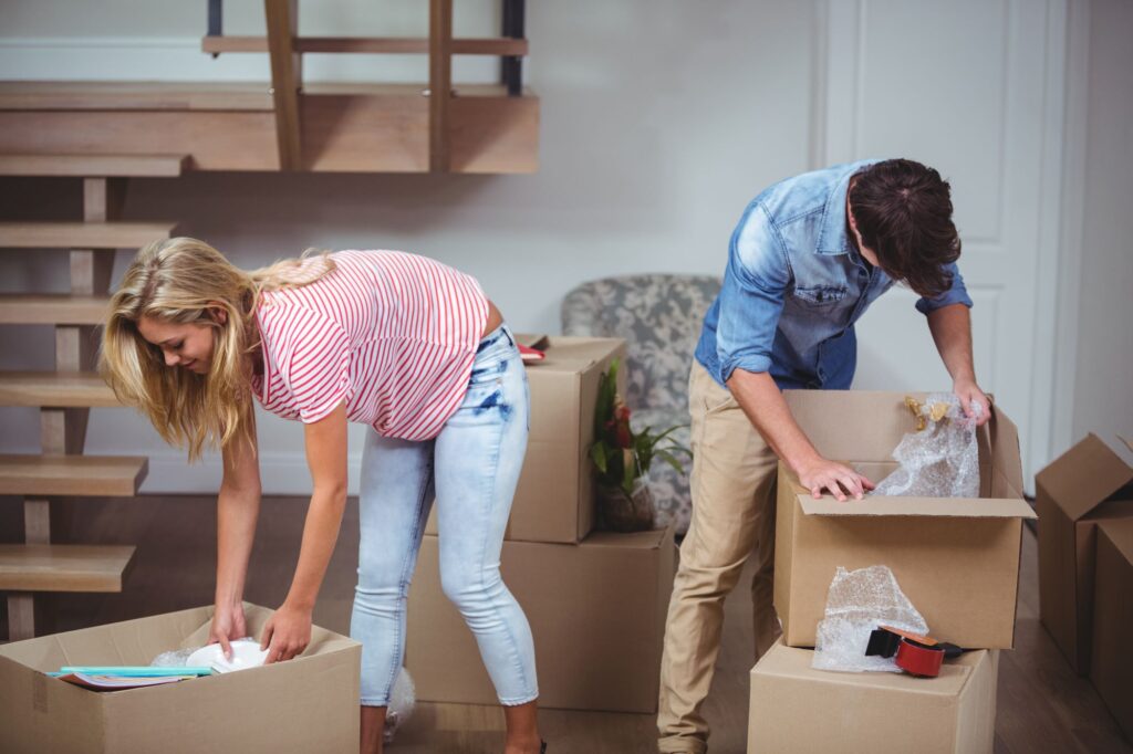 A couple is unpacking cardboard boxes after moving in.