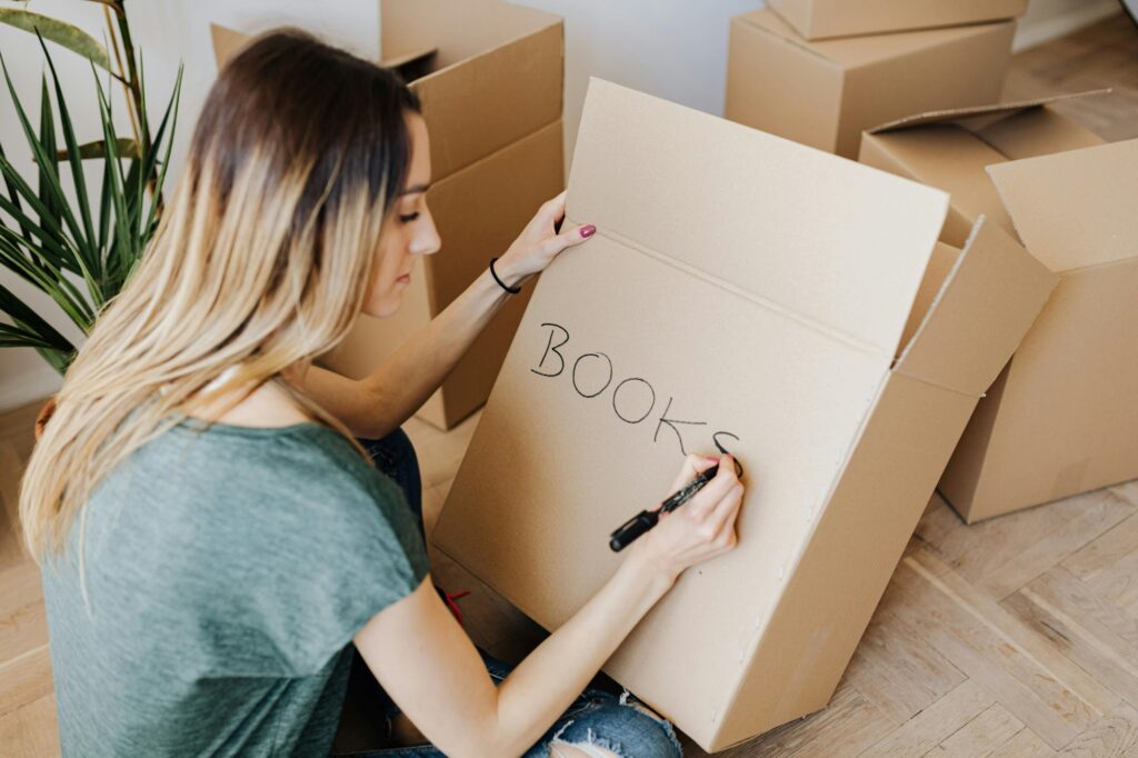 A student is labelling a carton and packing things herself