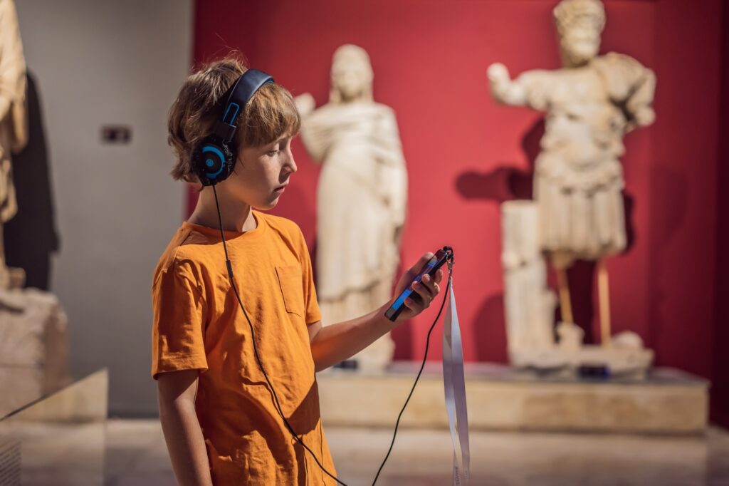 A boy is listening to the audio guide in a museum