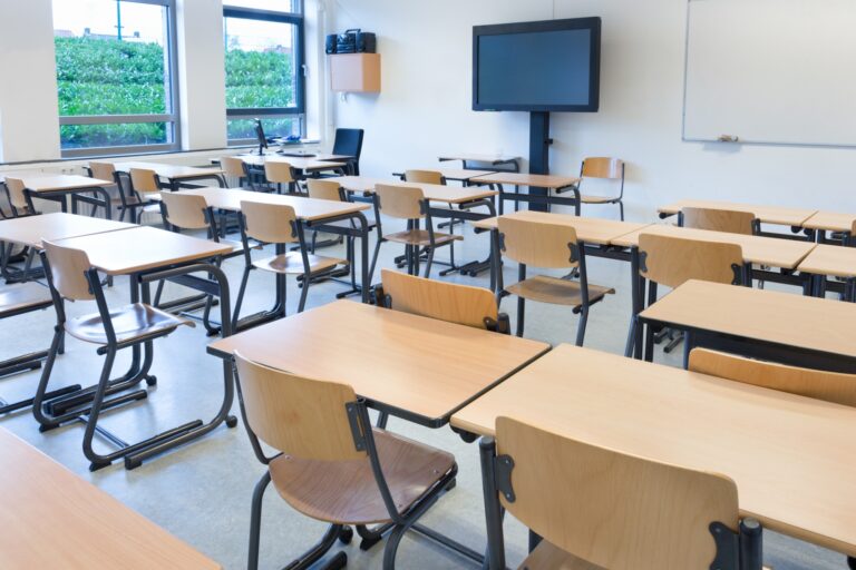 An empty classroom with tables and chairs in the concept of schools in Canary Wharf.